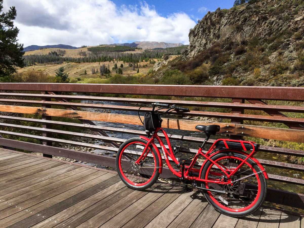 A pedal-assist bike is the way to go–and return. Parked here on a bridge over the reclaimed Blue River north of Breckenridge.