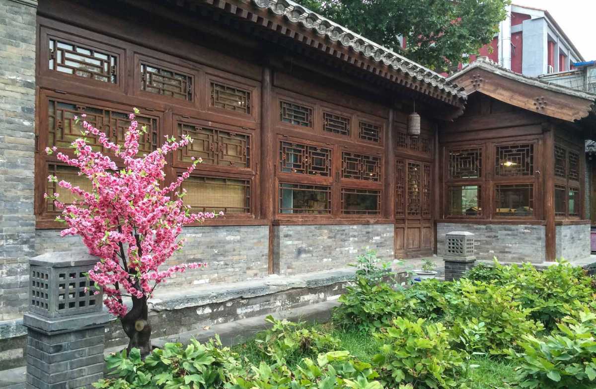 A garden and preserved wooden window screens at the Shijia Hutong Museum offer relief from the rows of gray buildings.