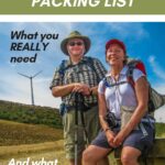 Tom and Kris Bartel on the Camino de Santiago carrying hiking backpacks and trekking poles on the sun-baked meseta — complete Camino de Santiago packing list: what you really need and what you don't, from TravelPast50.com.