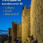 Medieval castle walls of Ávila, Spain, illuminated at dusk against a deep blue sky — Spain travel guide for travelers over 50 covering culture, food, and slow travel.