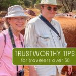 Kris and Tom Bartel of TravelPast50.com standing near elephants on safari in Africa — trustworthy travel tips for travelers over 50.
