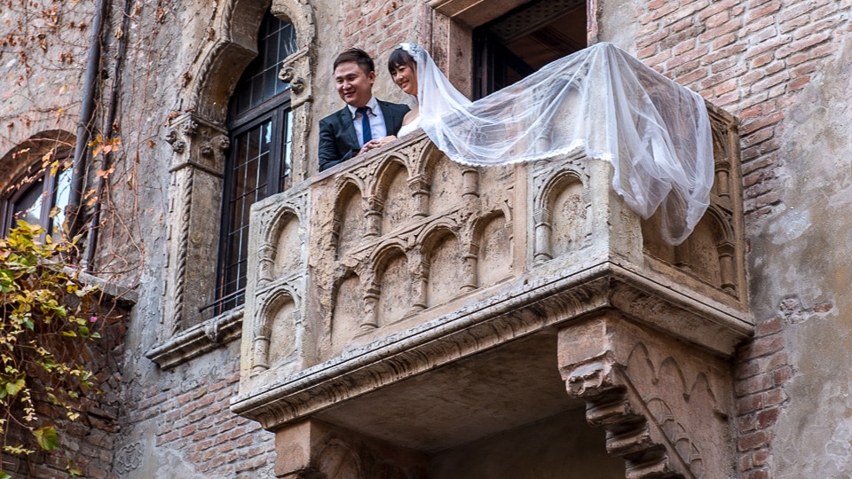 Newlyweds posing on Juliet's balcony in Verona, Italy.