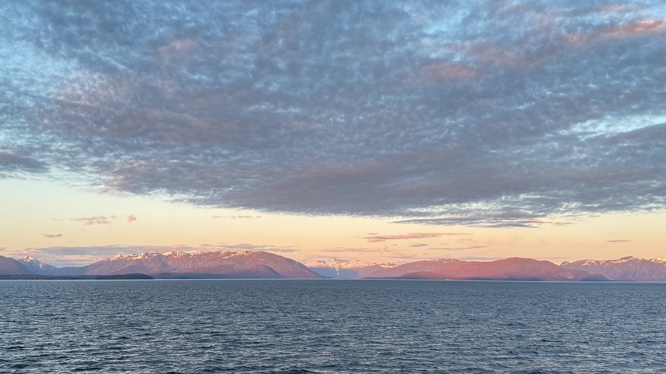 Sunset over Glacier Bay National Park, Alaska, with mountain reflections on calm water