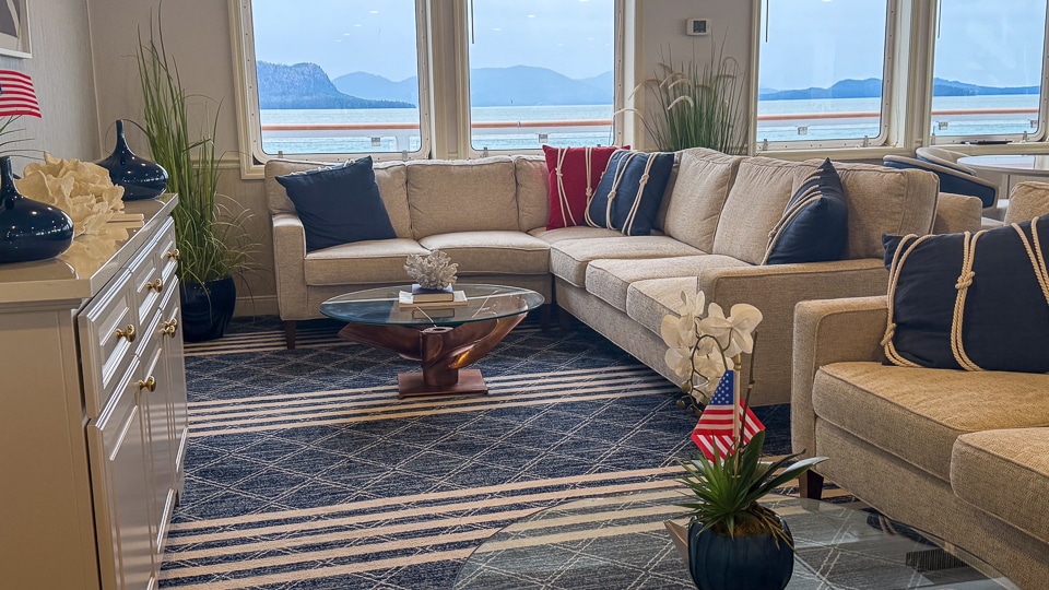 Sky Lounge aboard the American Constitution, a bright casual seating area with large windows overlooking the water