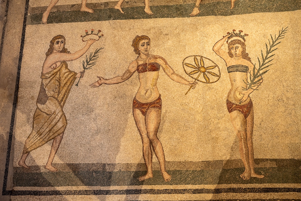 Victory scene from the Room of the Ten Maidens: a robed woman holding a crown and palm, a girl with a hoop, and a winner crowning herself