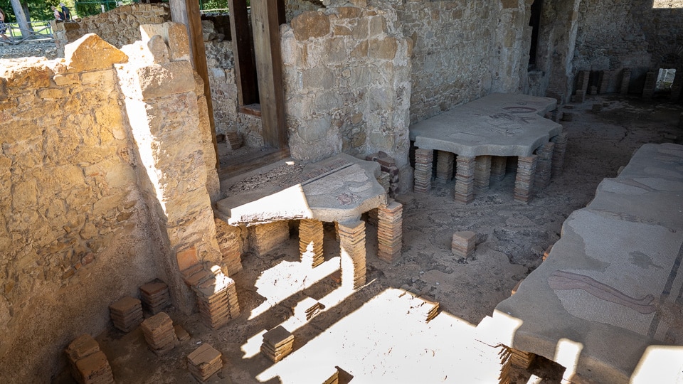 Brick hypocaust pillars holding up the raised floors of the villa’s heated baths, under a wooden protective roof