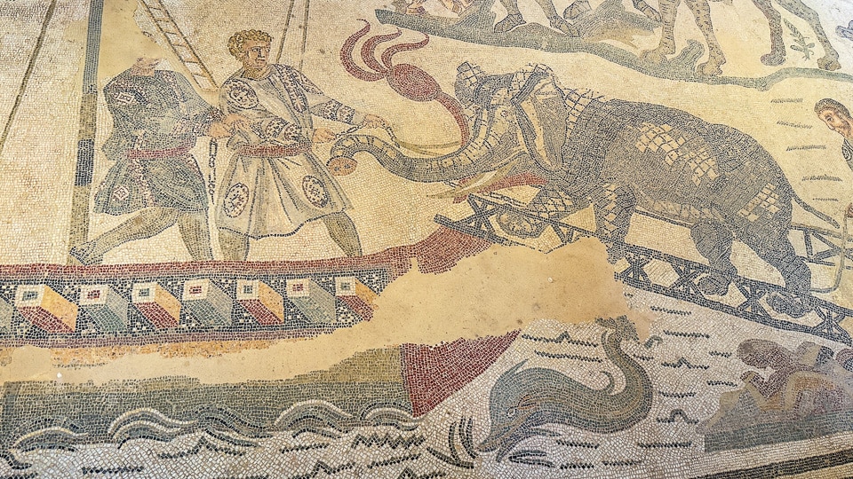 Two men guiding an elephant up a gangplank onto a ship, with a dolphin in the sea below, Great Hunt mosaic