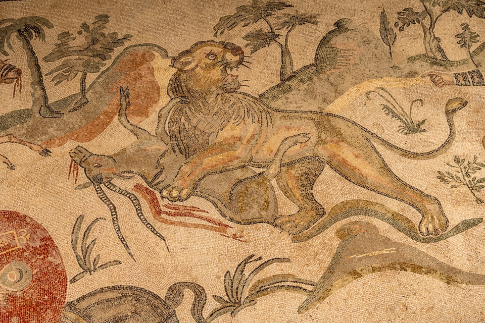 Lion bringing down a bleeding antelope among palm trees, Great Hunt mosaic at the Villa Romana del Casale