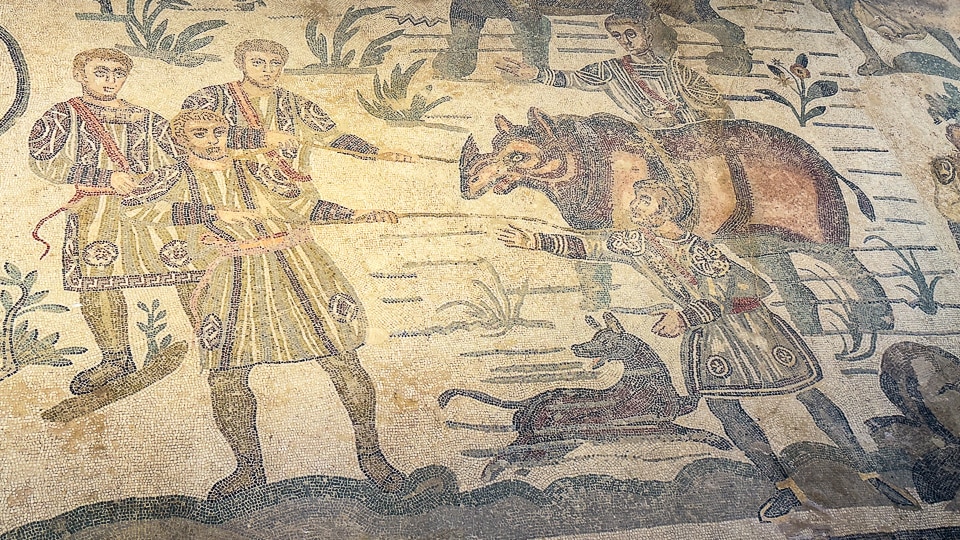 Hunters hauling a rhinoceros out of a marsh with ropes as a dog looks on, Great Hunt mosaic at the Villa Romana del Casale