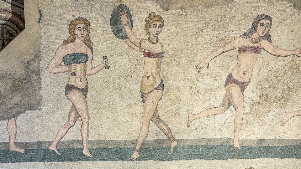 Three young women in two-piece outfits lifting hand weights, throwing a discus and running, Room of the Ten Maidens mosaic